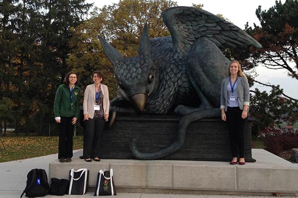 Women in computing standing in front of statue 