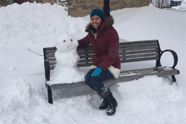 Susan sitting on bench next to snowman 