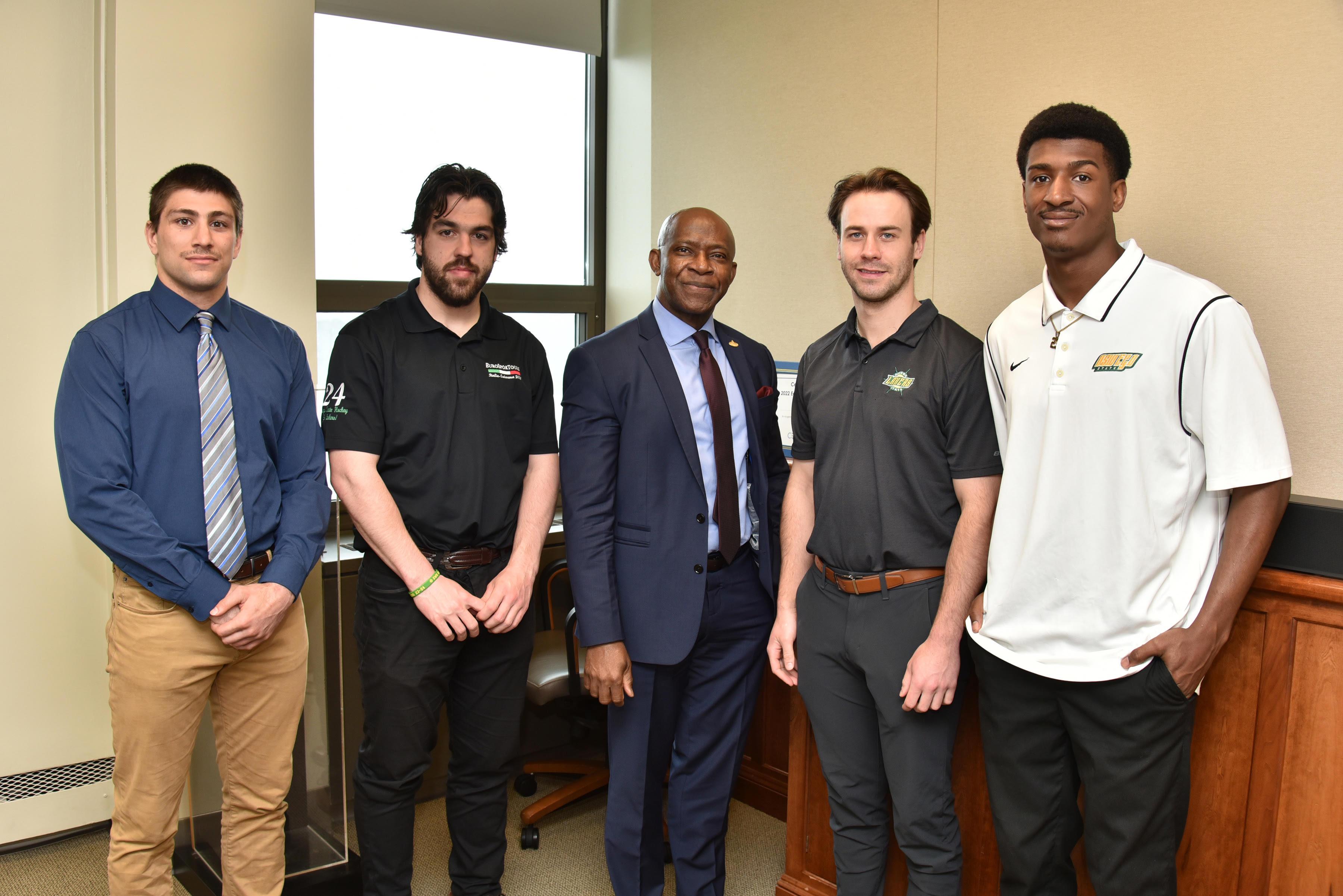 Four Laker student-athletes recently earned All-American recognition: With President Peter O. Nwosu (center) are, from left, Charlie Grygas, wrestling; Shane Bull, men's hockey; Tyler Flack, men's hockey; and Jeremiah Sparks, men's basketball