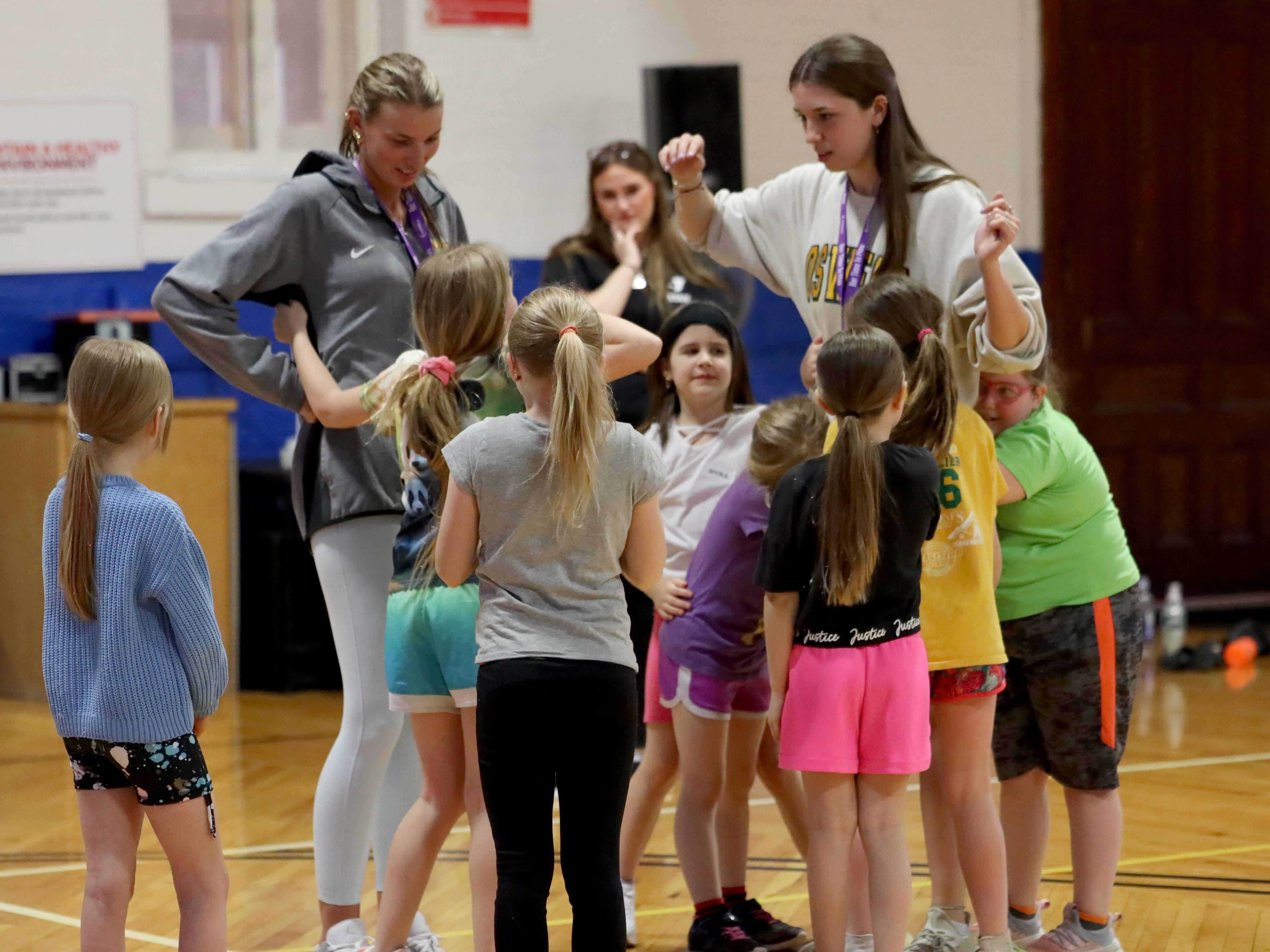Two members of the Laker women's basketball team enjoy working with girls in the Her Time To Play program at the Oswego YMCA