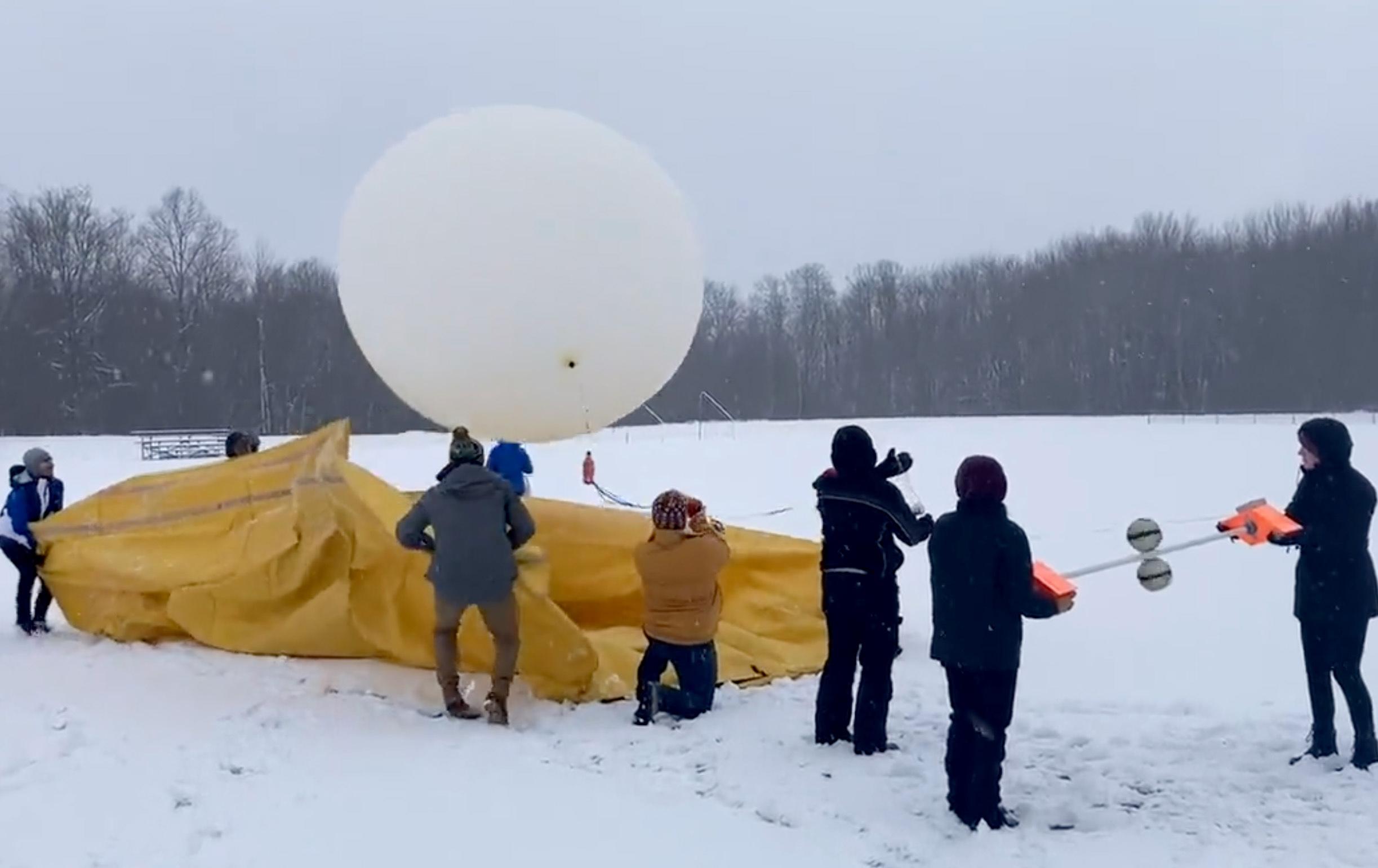 Students taking part in a lake-effect lighting study launch a huge weather balloon with attached instrumentation to measure conditions inside a winter storm cloud.