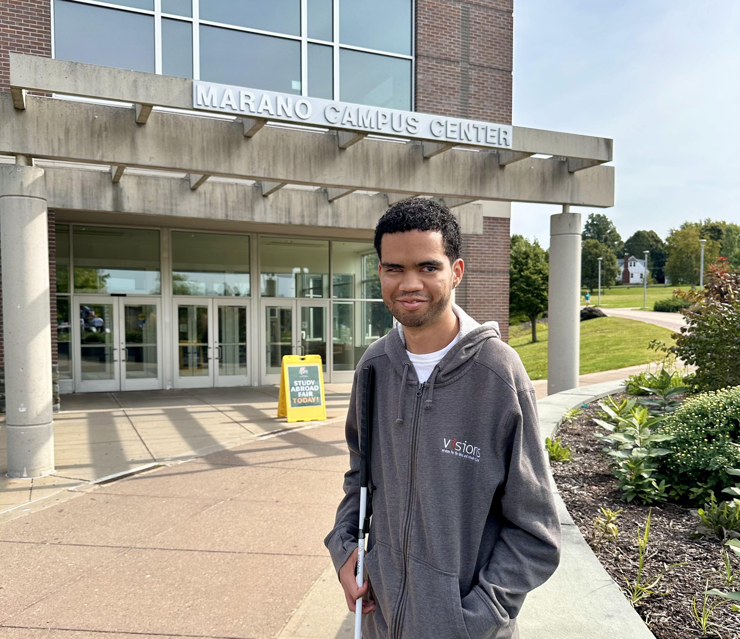 Student Luis Perez-Rivera stands outside in front of the Marano Campus Center wearing a grey hoodie.