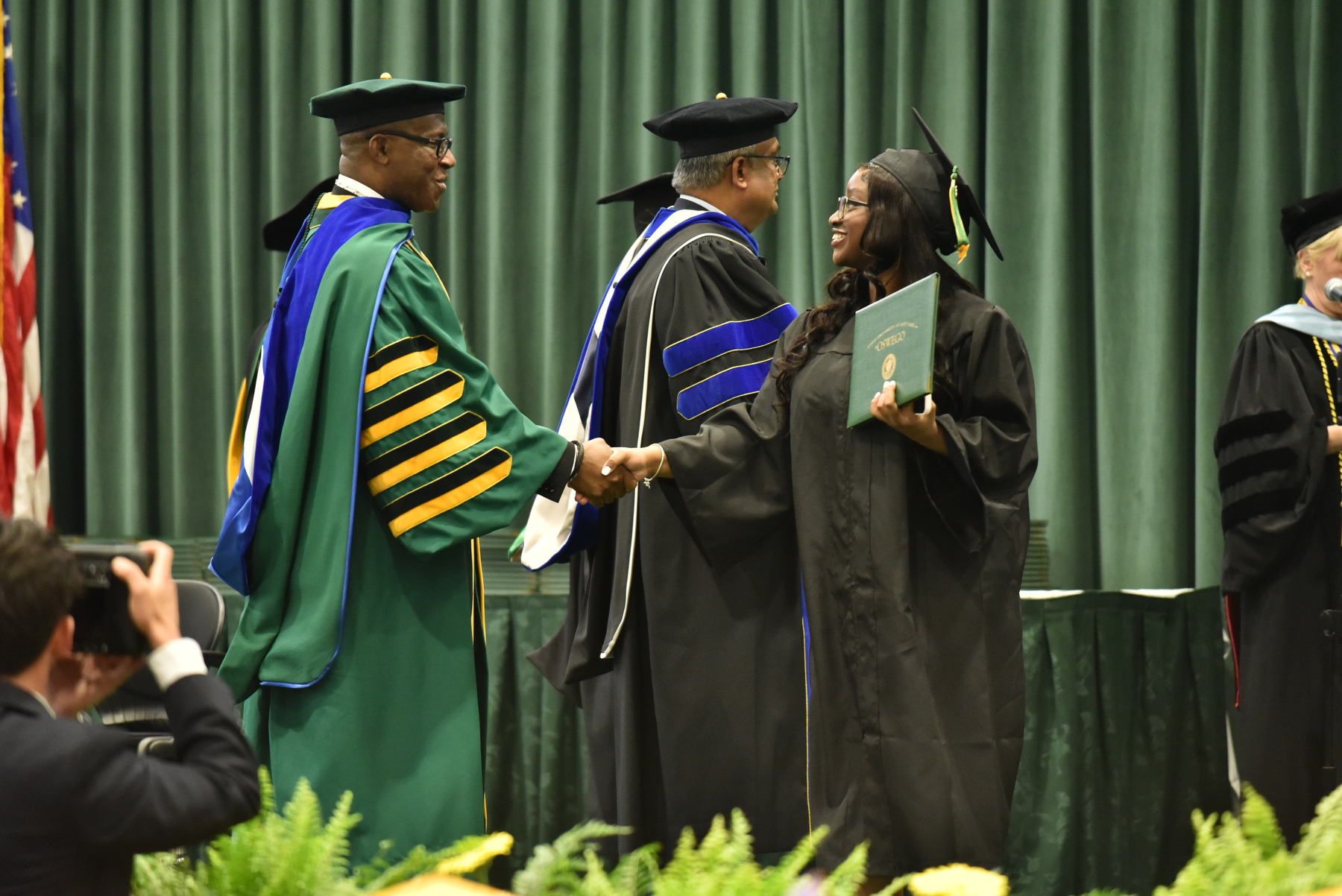 Each graduate's name is announced as they walk across the commencement platform before shaking hands with their dean –- in this case Prabakar Kothandaraman from the School of Business –- and President Peter O. Nwosu.