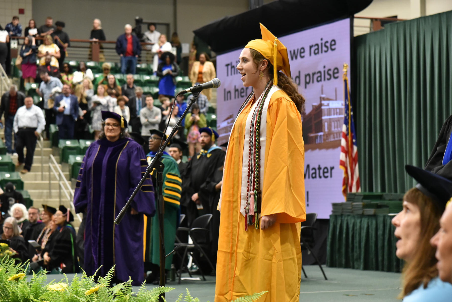 Mackenzie Shields, who graduated summa cum laude with degrees in music and journalism, leads the singing of the Alma Mater at the conclusion of the School of Communication, Media and the Arts and School of Education ceremony.
