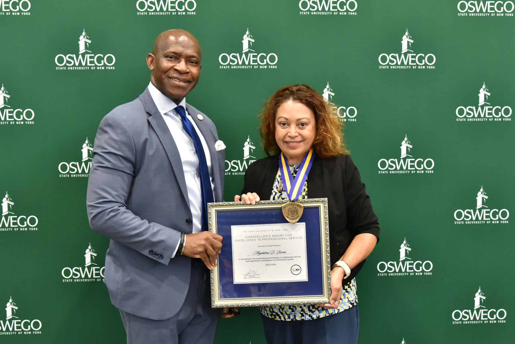 Magdalena (Maggie) D. Rivera, assistant dean of students for student outreach and support, receives her Chancellor's Award in Professional Service and congratulations from President Peter O. Nwosu at the Opening Breakfast. Watch Oswego Today for a full story on her award.