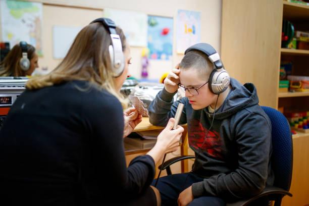 student wearing headphones working with a student teacher